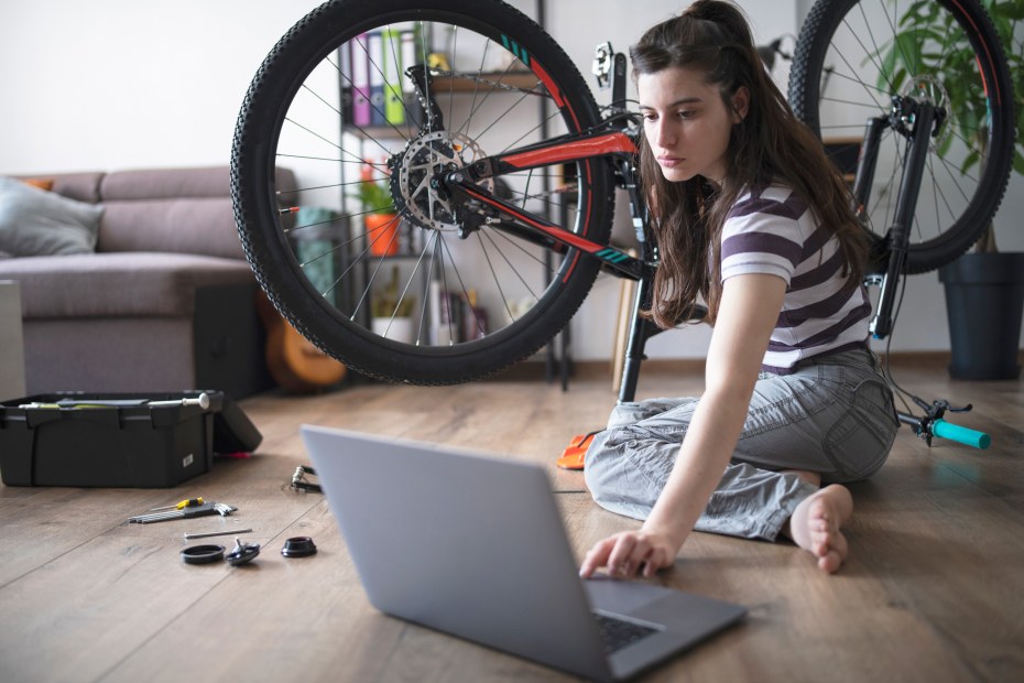 A woman follows a tutorial to fix her bike.