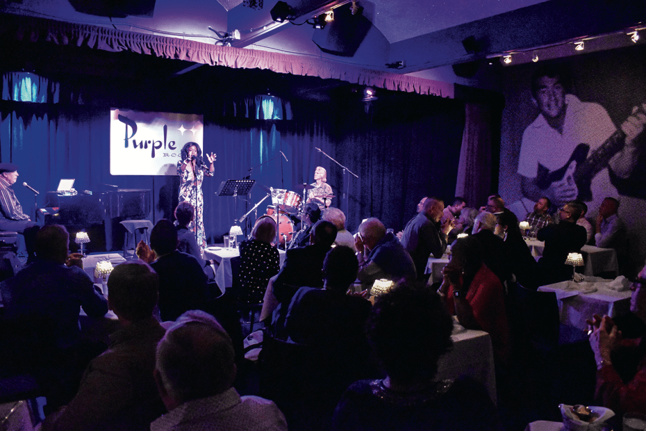 a singer performs onstage for an intimate crowd in the Purple Room in Palm Springs