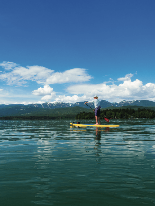 a paddleboarder crosses the waters of whitefish lake in montana