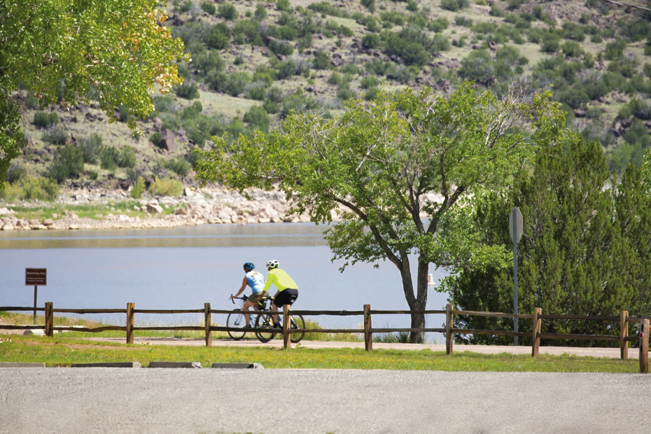 cyclists ride along a path beside Lyman Lake in Arizona