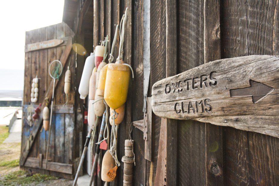 Bouys and a sign for oysters and clams hang on a shed at a shellfish farm on Orcas Island, Washington. 