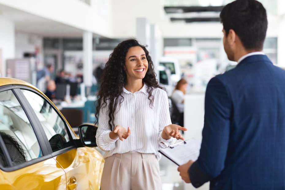 A woman talks to a car sales person.
