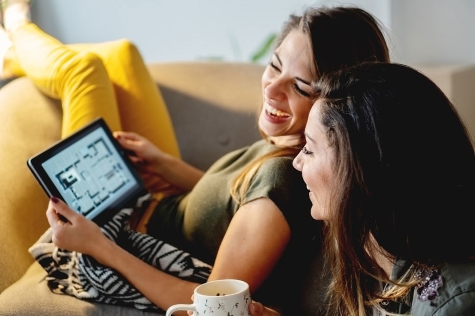 Two women look at an apartment floorplan on a tablet.