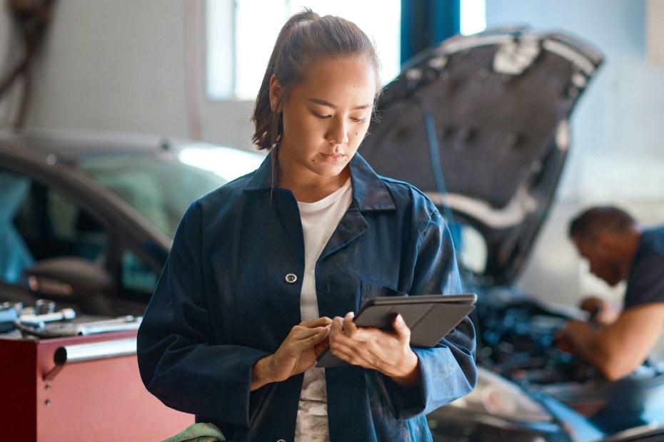 A female mechanic looks at a diagnostics report.