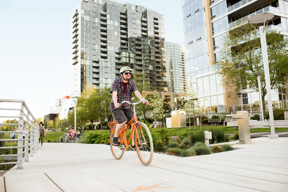 A person rides an orange bike on the South Waterfront Greenway in Portland, Oregon.