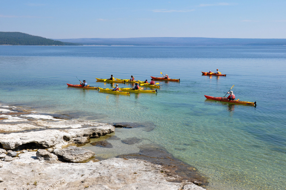 A group kayaking in Yellowstone National Park, Wyoming on a clear day.