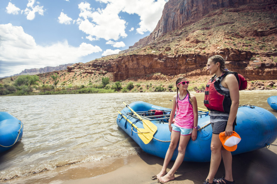 Sisters stand against a blue raft in the Grand Canyon.