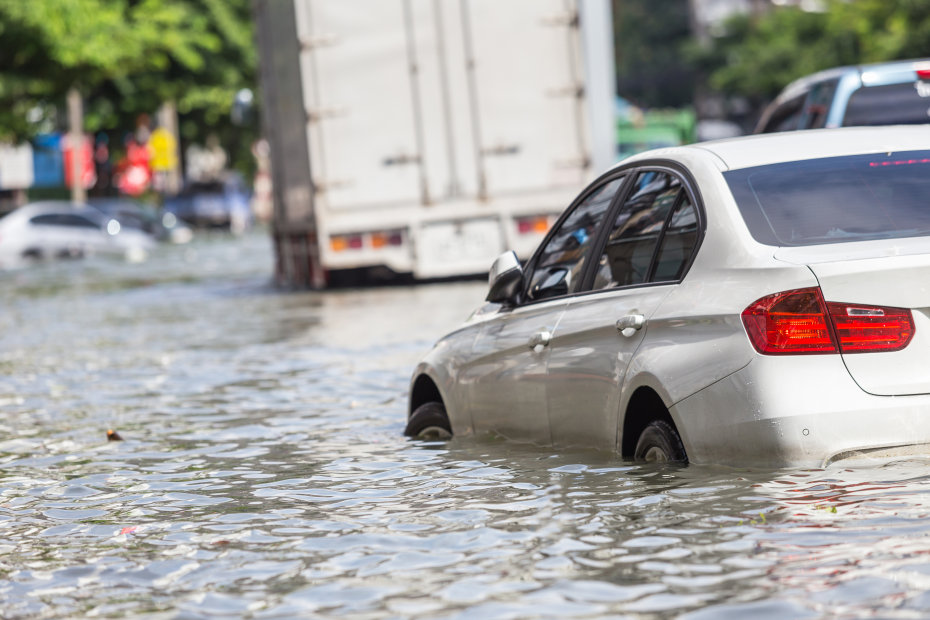 Flood waters nearly submerge the tires of a white car.