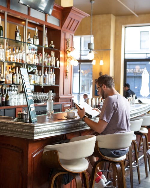 A man sits at the bar and reads the menu inside Cafe de la Presse on Grant Street in San Francisco's Union Square.