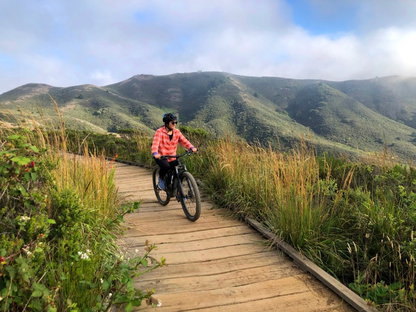 A woman rides on a boardwalk in the Marin Headlands in California.