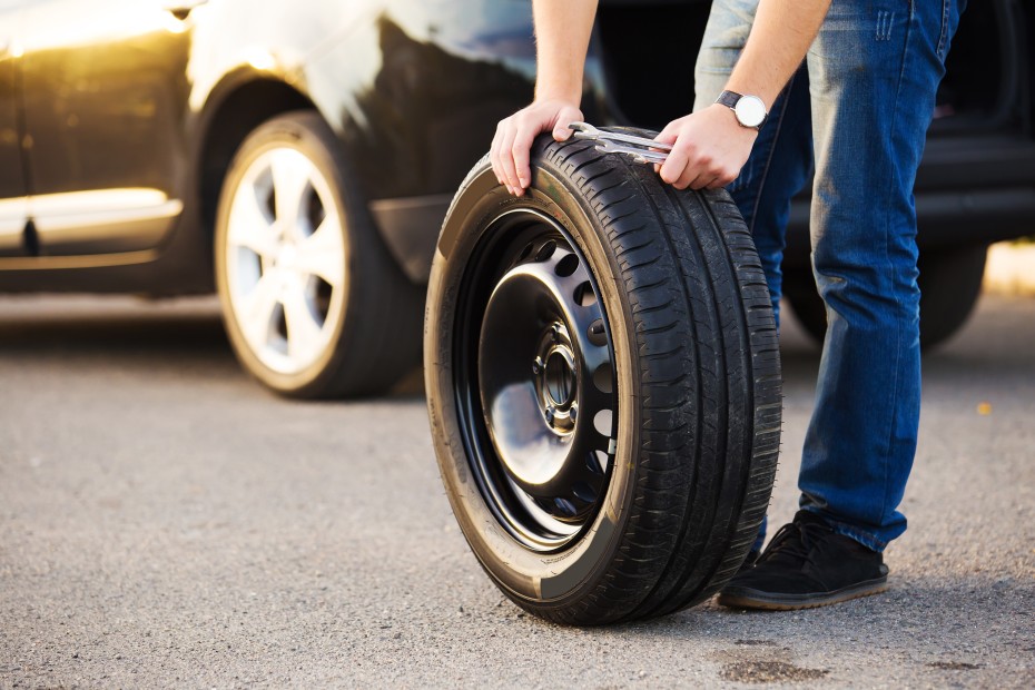 A person inspects the tread on their spare tire.