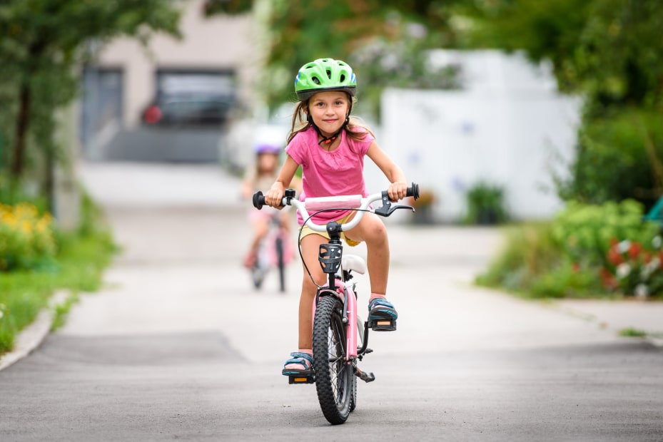 A young girl and her sister ride their bikes to school.