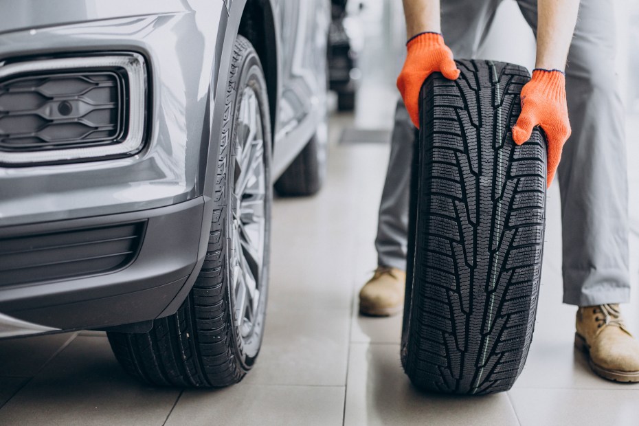 A mechanic inspects a tire before installing it on an SUV.