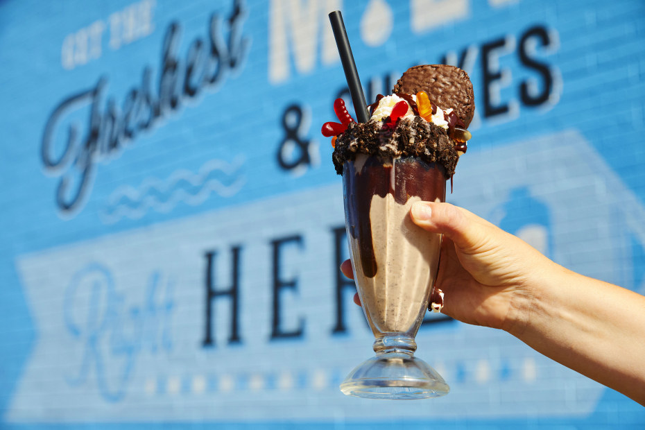 A glass of the The Dirt Stack milkshake, which is a vanilla shake in a chocolate syurp lined glass, topped with oreo crumble, gummy worms and a hostess cupcake, from Danzeisen Dairy Creamery Store.