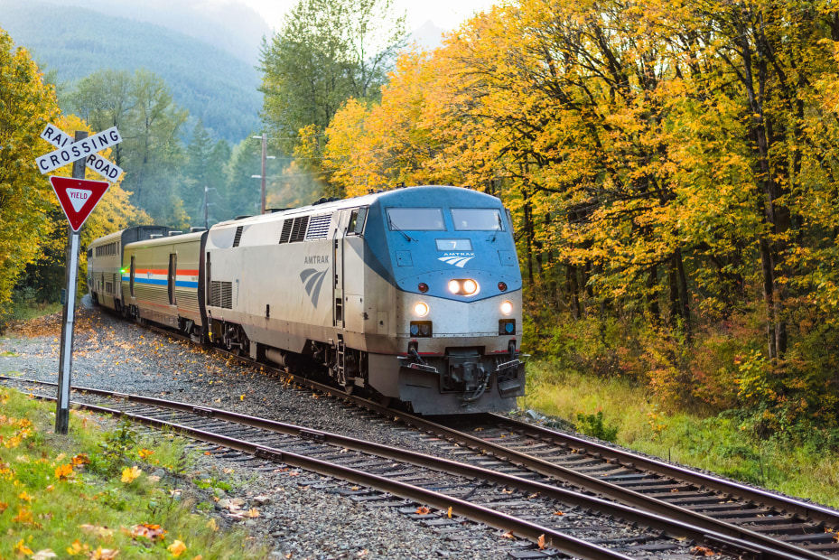 An eastbound Amtrak Empire Builder train passes through the Cascade Mountains near Skykomish, Washington as the trees turn fall colors.