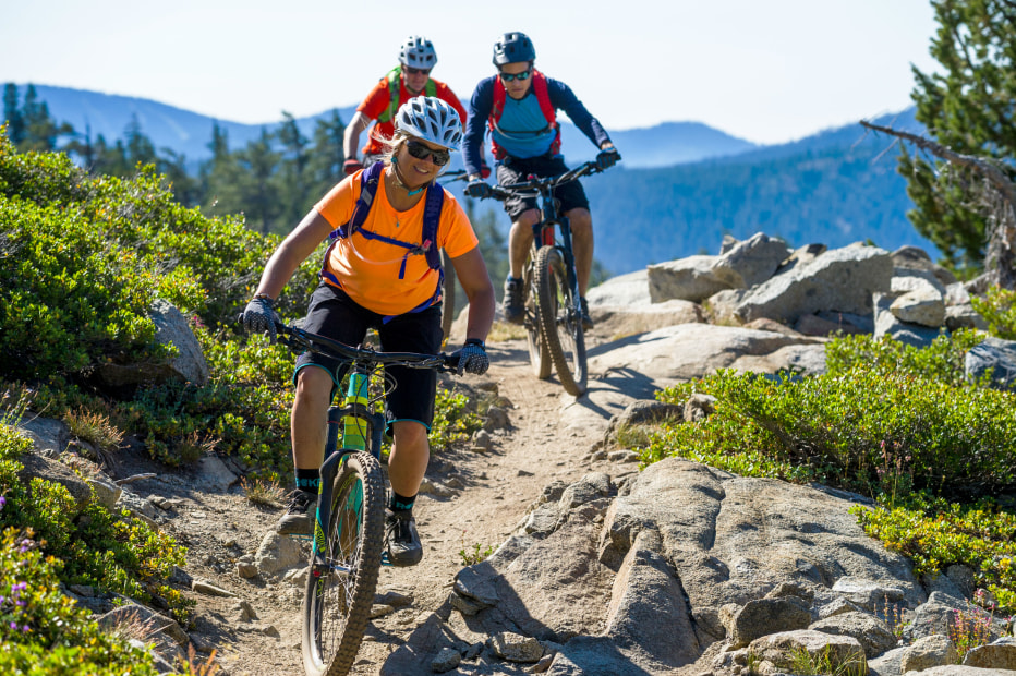 On a clear sunny day, three mountain bikers ride along the Donner Lake Rim Trail in Truckee, California.