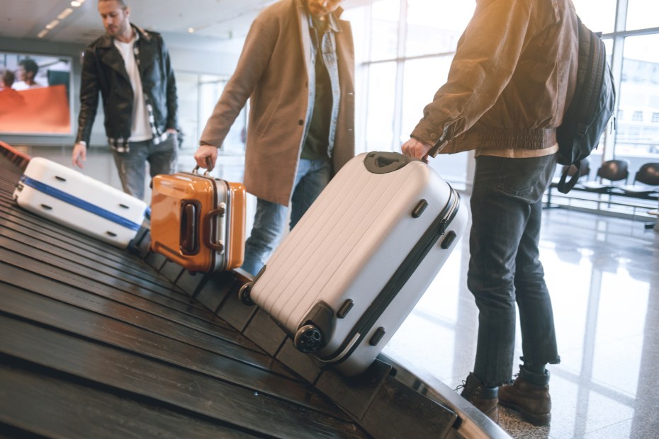 Travelers retrieve their bags from a baggage carousel at the airport.