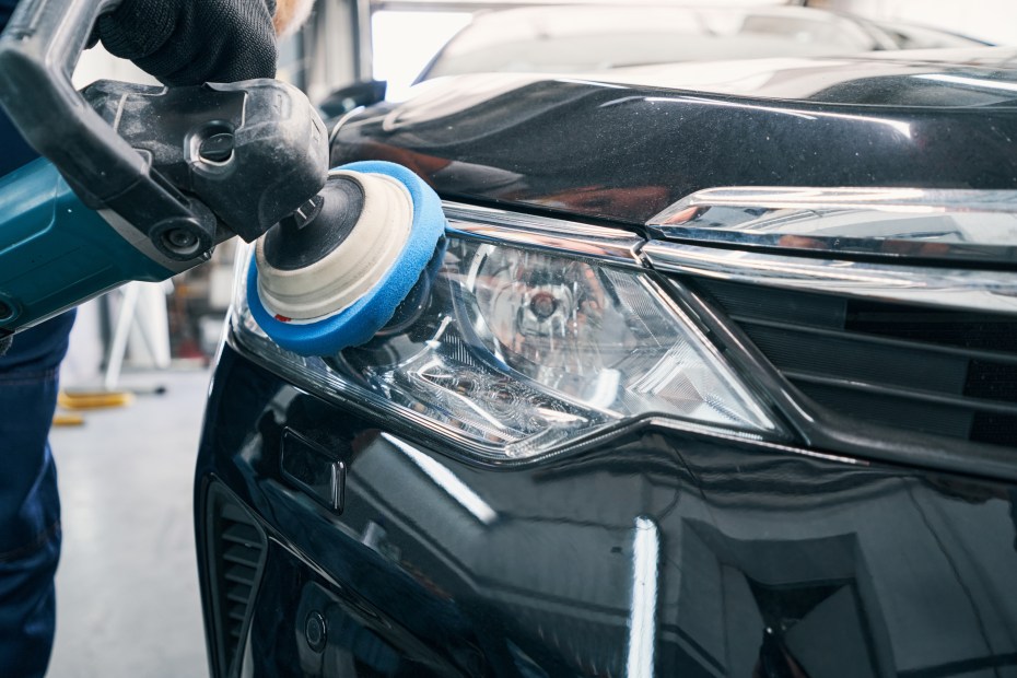 A professional car detailer polishes a car headlight.