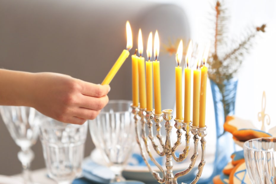 A person lights the final candle on a menorah.