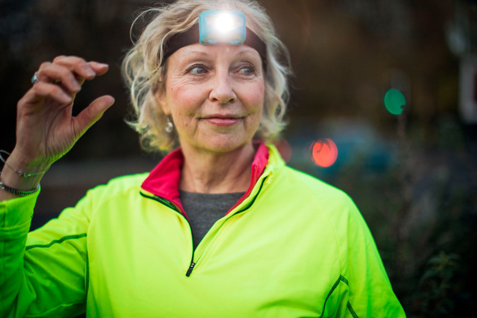 A runner in a neon green shirt turns on her headlamp.