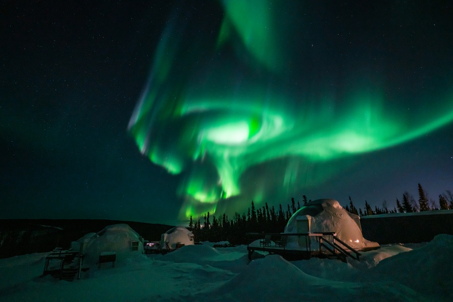 Green northern lights swirl over the igloos in Fairbanks, Alaska.