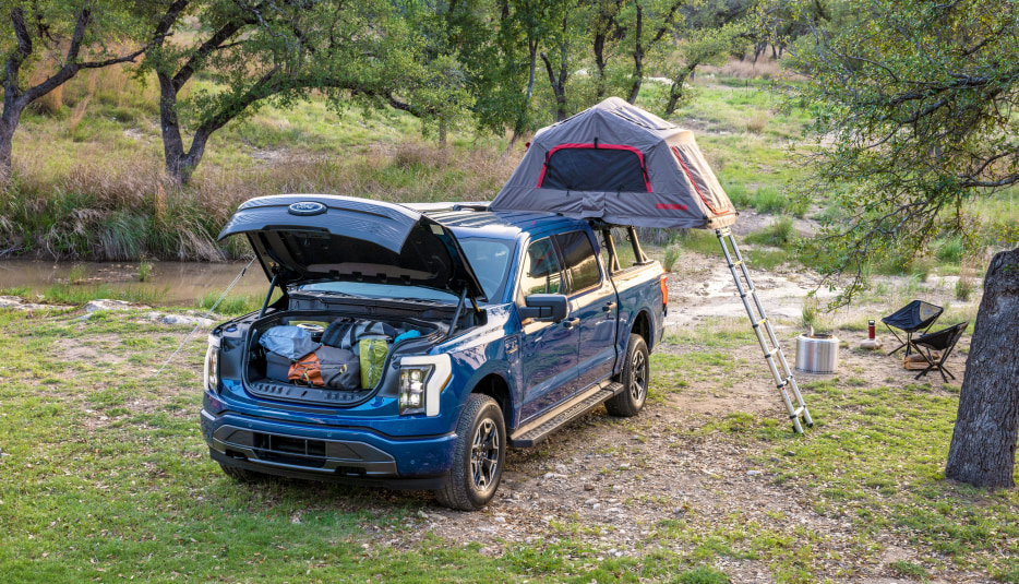 Ford F-150 Lightning XLT set up for camping with a tent off the bend and a full gear frunk.