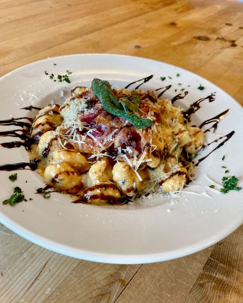 Gnocchi in parmesan sage cream with fried sage, pancetta, and balsamic reduction on a table at Bella's Bistro.