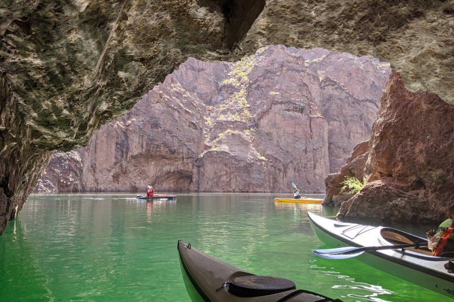 Kayakers look out of Emerald Cove with the green Colorado River water beneath them.