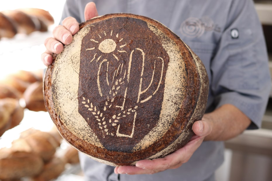 A baker holds out a loaf of bread from Barrio Bread in Tucson, Arizona.