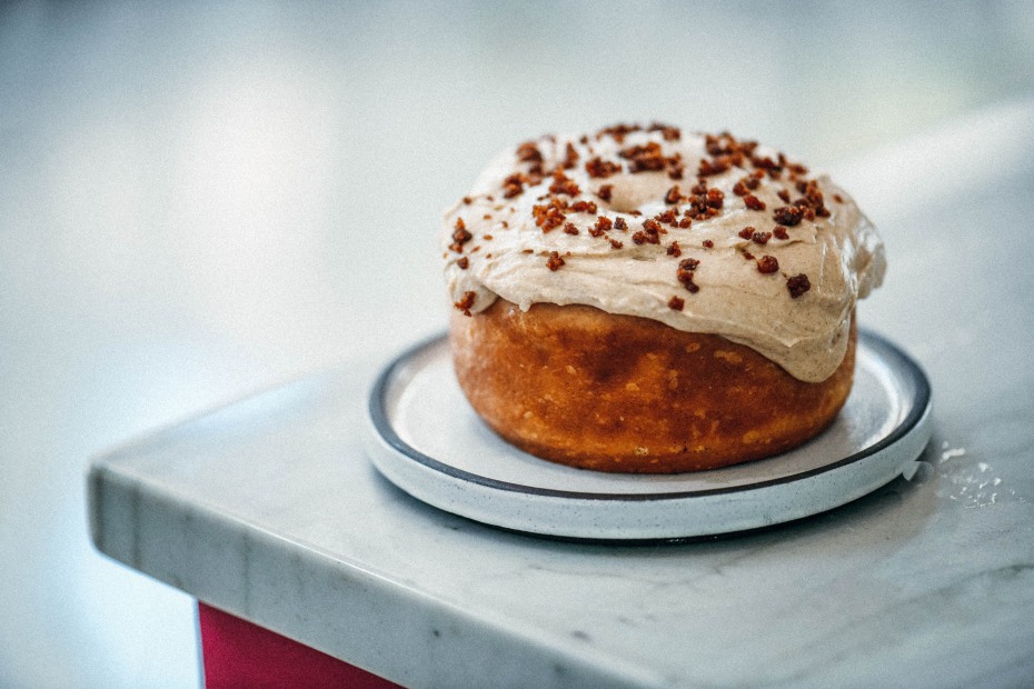 Kinnamons' cinnamon roll topped with Maple Syrup and Cream Cheese spread and chopped applewood smoked bacon.