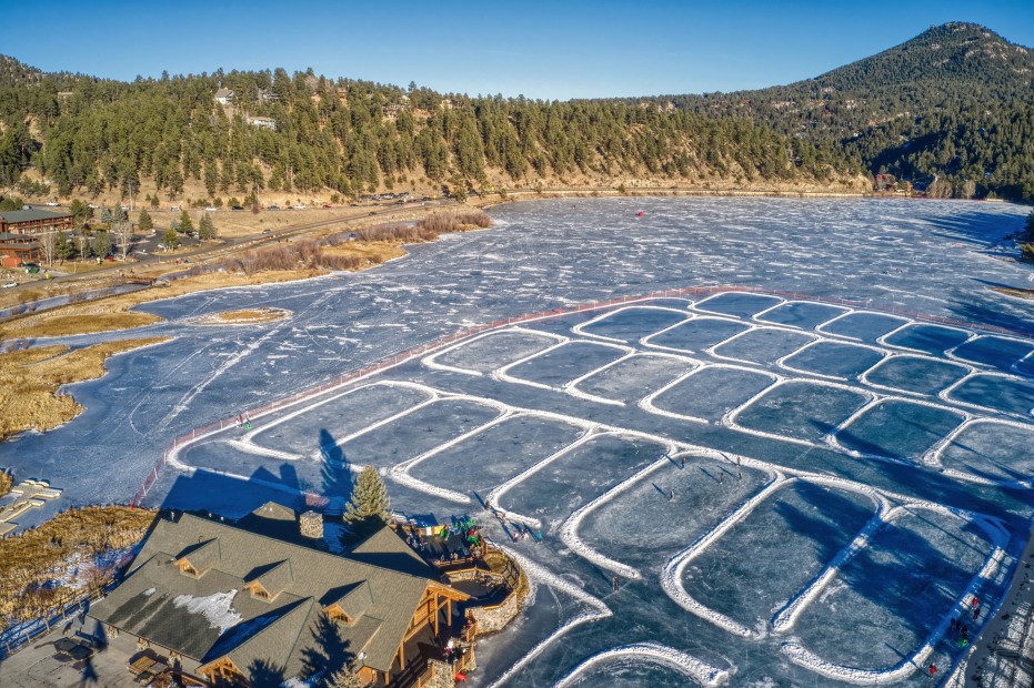 More than a dozen ice rinks created on frozen Evergreen Lake in Evergreen Colorado on a sunny day.