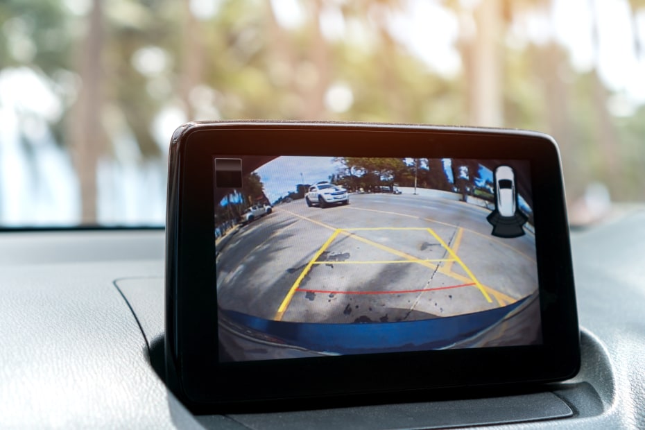 A dashboard back-up camera shows a car driving behind the vehicle.