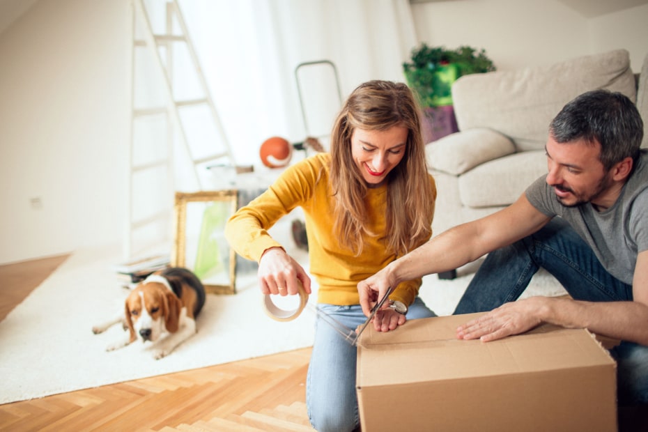 A couple tape up a box while packing up their home.