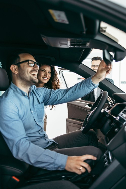 A couple look at a new car inside a car dealership showroom.