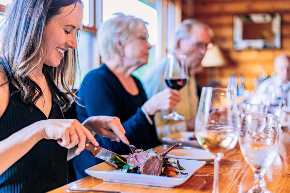 A woman cuts into the signature rack of lamb at Big Hole Lodge on Wise River, Montana.