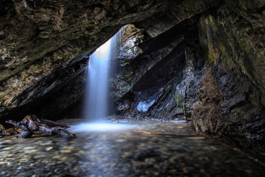 Water falls through a hole in the rock at Donut Falls in Big Cottonwood Canyon, Utah.