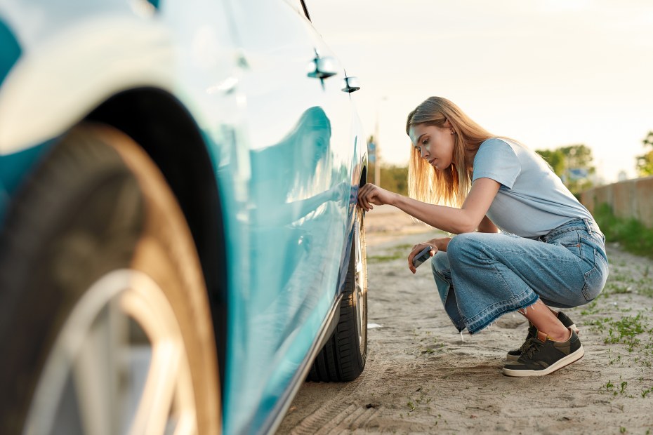 A woman inspects her tire after hitting a pothole. 