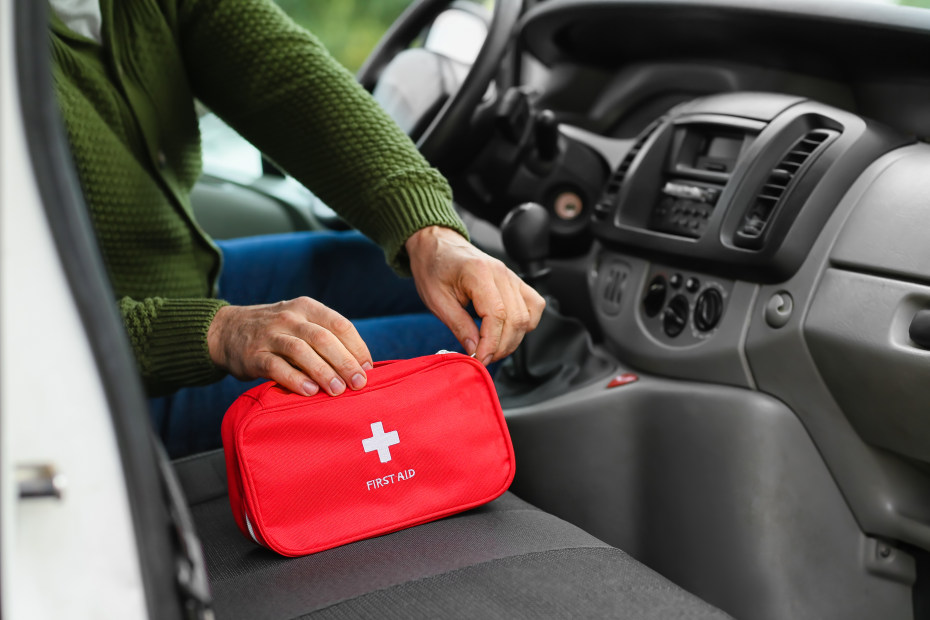 A driver unzips their first aid kit in their car.