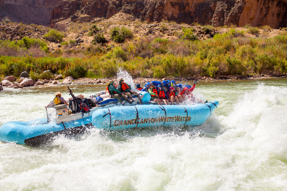 Rafters ride down the Colorado River in a blue raft with Grand Canyon Whitewater.