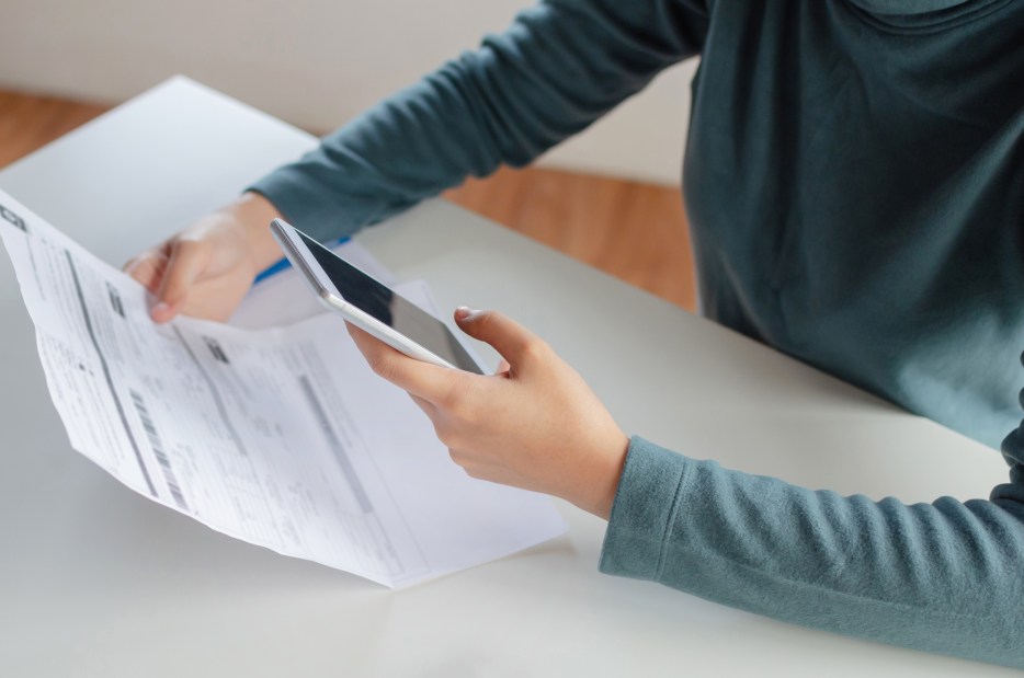 A woman reviews a medical bill at her dining table.