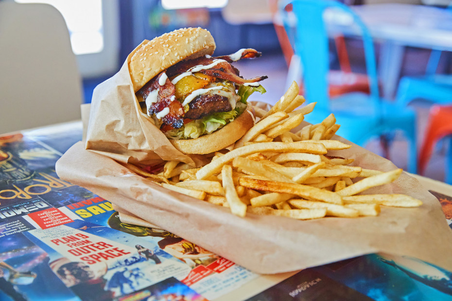 Hamburger with bacon and a side fries on a comic-covered table at Nurdberger in Gobe, Arizona.
