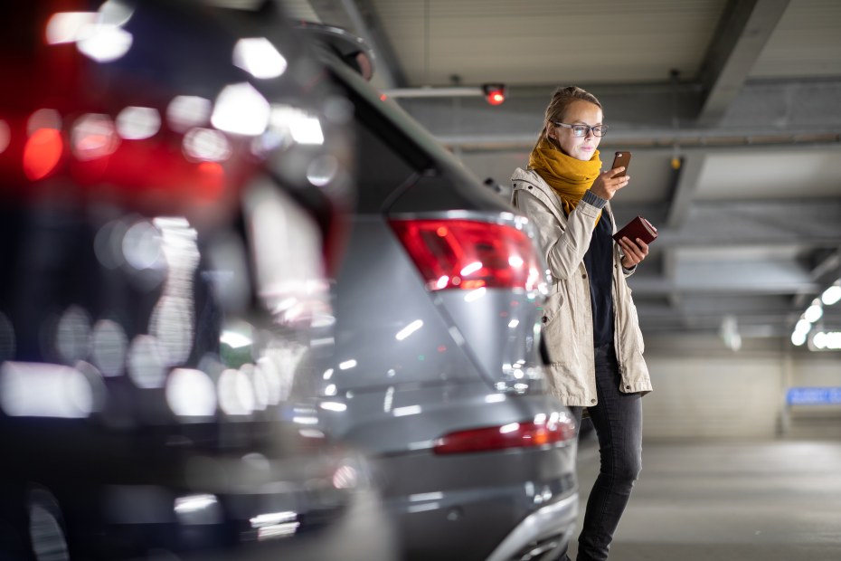 A woman uses a Bluetooth tracker to find her parked car in a parking garage.