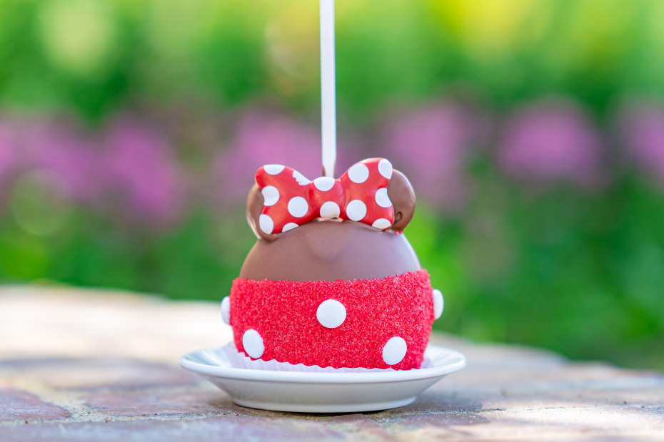 Sprinkle-dipped Minnie Mouse caramel apple on a table at Disneyland.