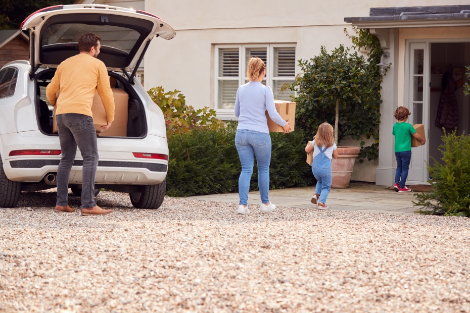 A family moves boxes out of their SUV into their new home.