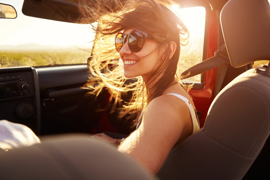 A woman sits in the front passenger seat of a Jeep with the window down.