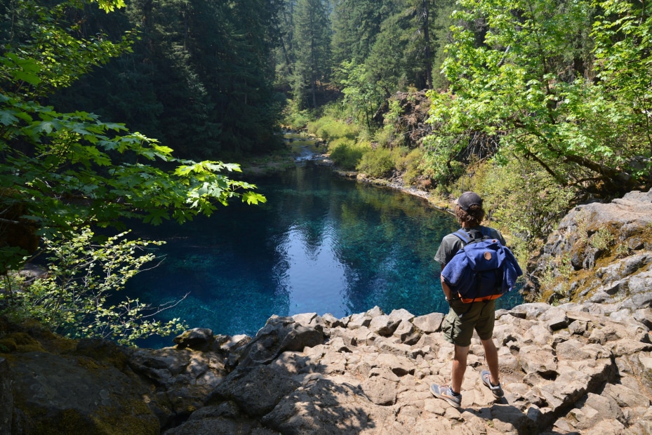 A hiker stands above the otherworldly Blue Pool beneath Tamolitch Falls on the McKenzie River in Oregon.
