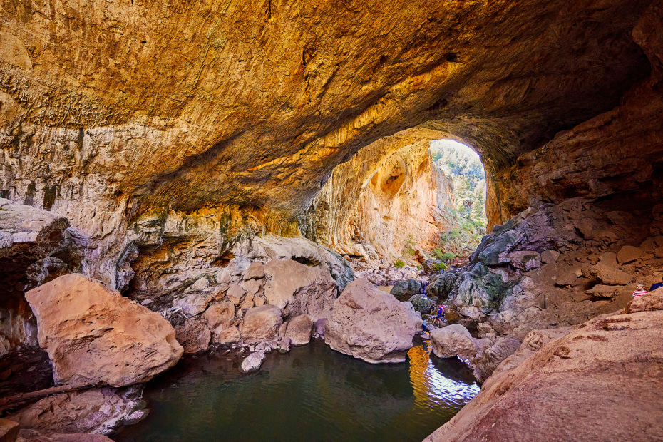 Hikers make their way through a rock tunnel in Tonto Natural Bridge State Park near Payson.