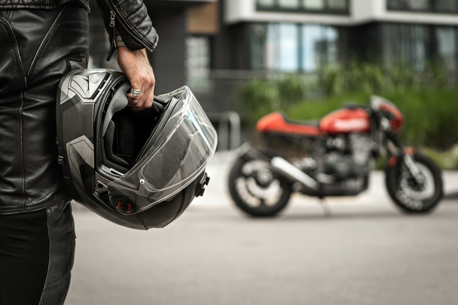 A motorcycle rider holds their helmet.