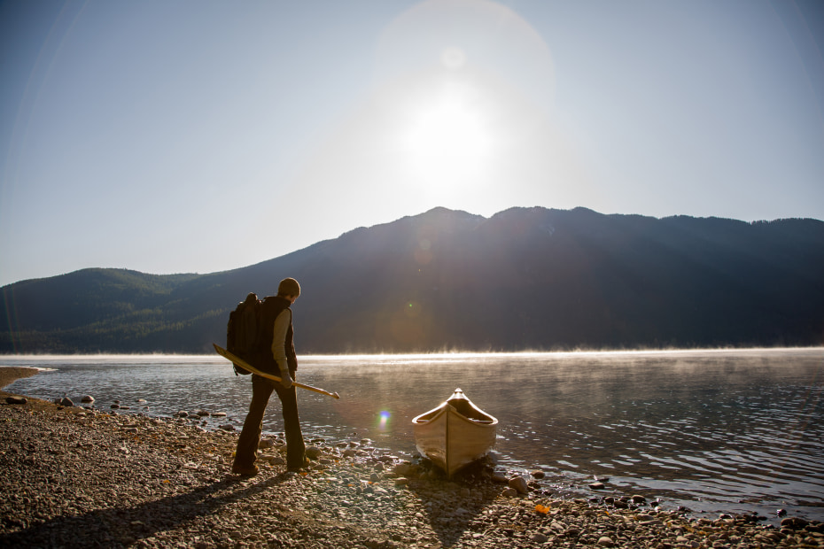 A person readies a canoe on the shore of Lake McDonald in Glacier National Park.