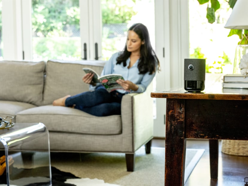 A woman lounges on the couch with an indoor security camera pointed at the door.